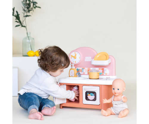 פעוט משחק במטבח הבובות Smoby Baby Nurse ליד בובת תינוק