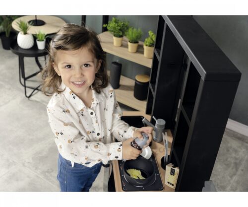 ילדה טוחנת מלח ופלפל ליד הוויטרינה של מטבח Smoby Loft