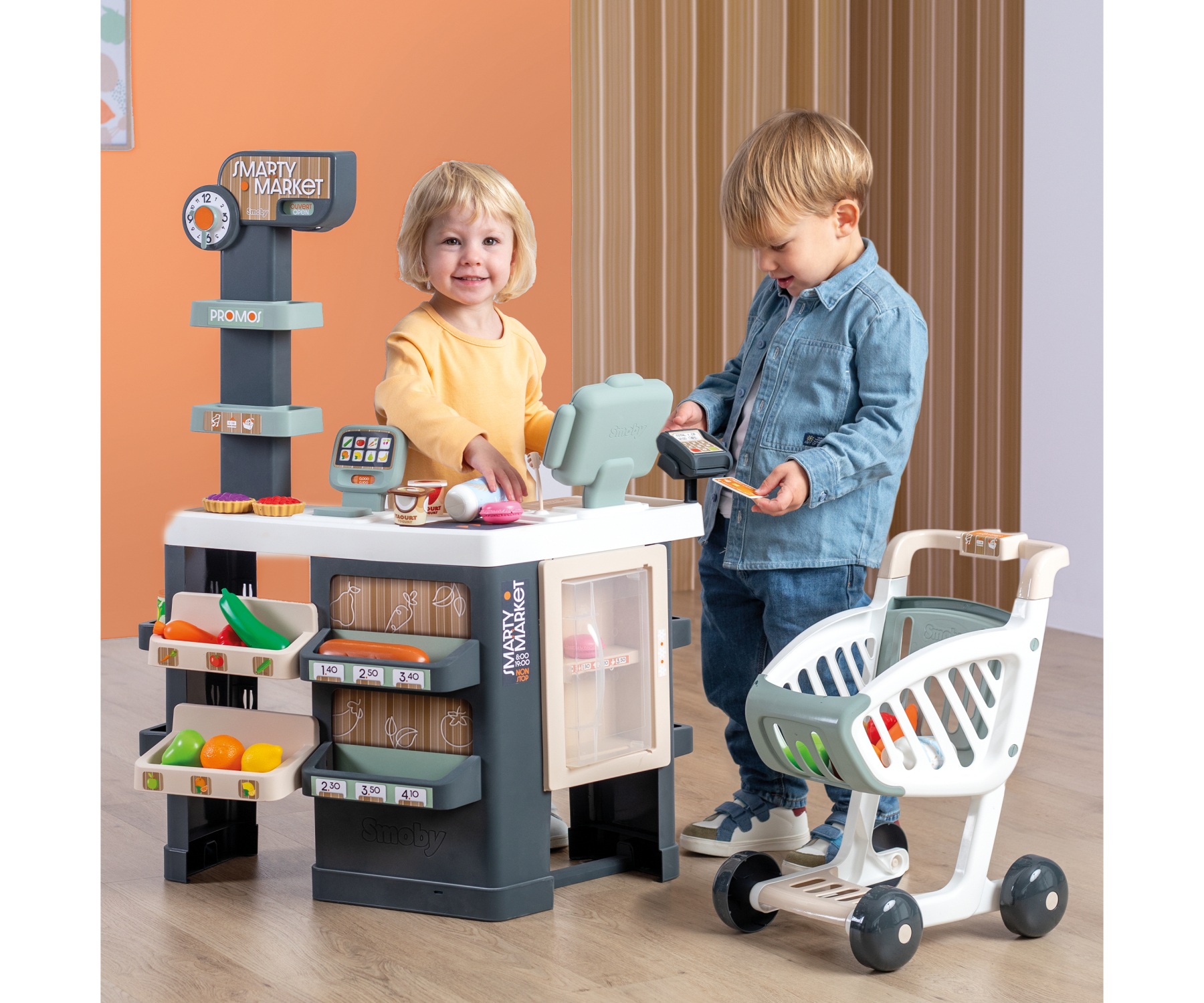 שני ילדים משחקים בקופה ועם עגלת הקניות של Smoby Smarty Market
